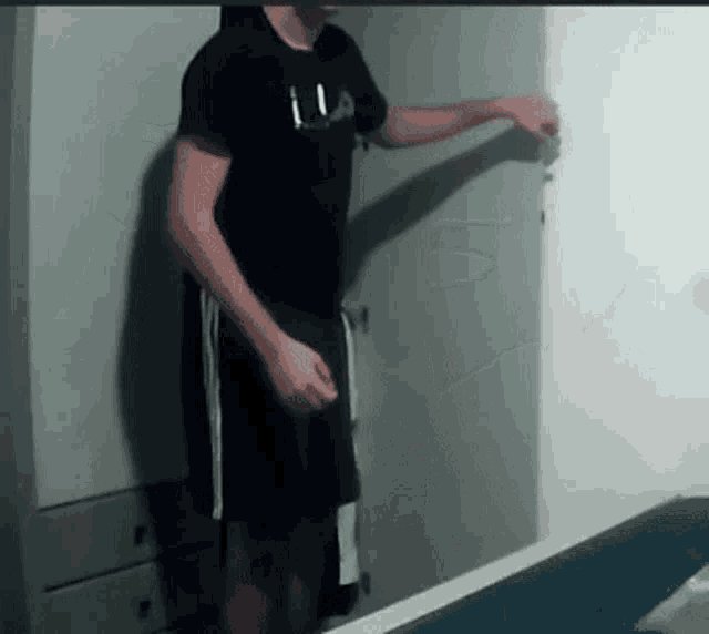 a man wearing a black fila shirt is standing in front of a door