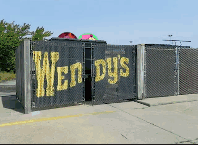 a chain link fence has wendy 's written on it