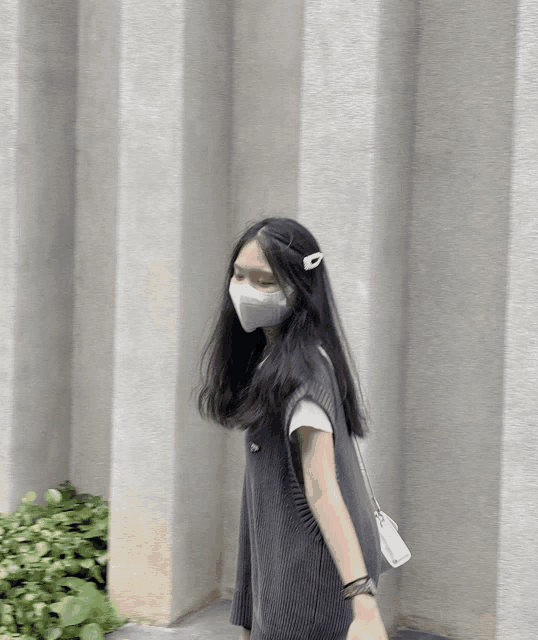 a woman wearing a white face mask and a gray vest