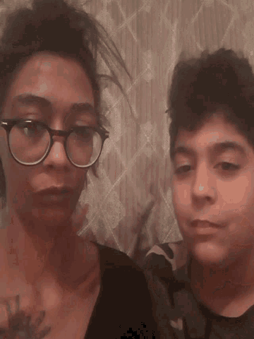 a woman wearing glasses is kissing another woman 's cheek