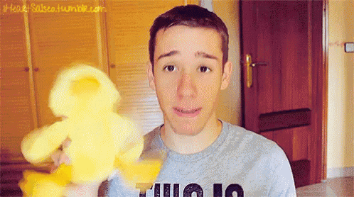 a young man is holding a yellow teddy bear and wearing a shirt that says " julio 10 "