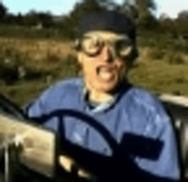 a man wearing goggles is driving a car in a field .
