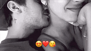 a man with a cross tattoo on his neck is kissing a woman 's neck .