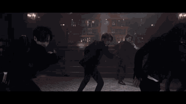 a group of men are dancing in a dark room