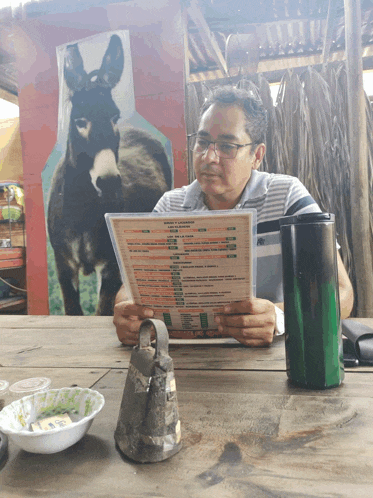 a man sitting at a table looking at a menu