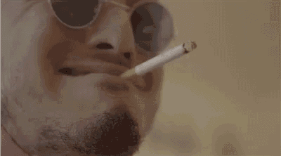 a man with a beard and sunglasses is smoking a cigarette in his mouth .