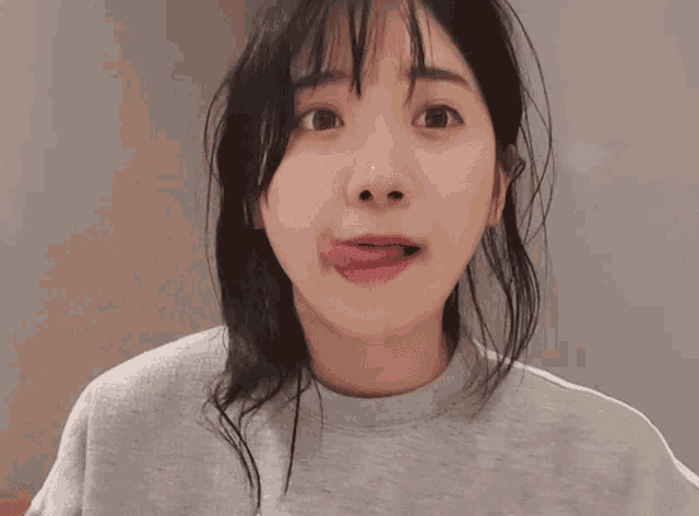 a woman sticking her tongue out and wearing a grey shirt
