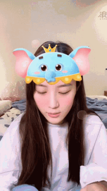 a woman wearing a blue elephant mask with a crown on top