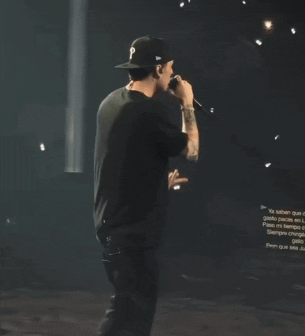 a man singing into a microphone while wearing a baseball cap with the letter p on it