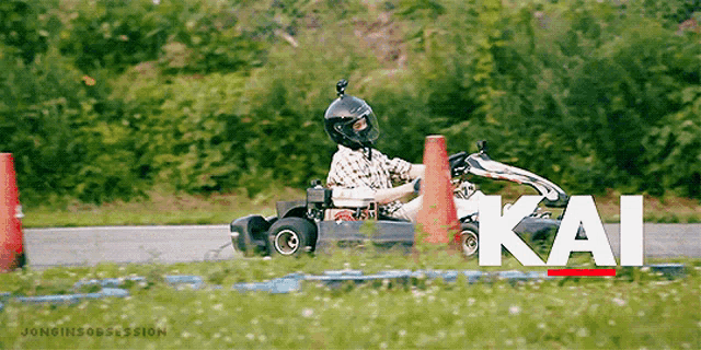 a man wearing a helmet is driving a go kart on a track with the word kai written on it