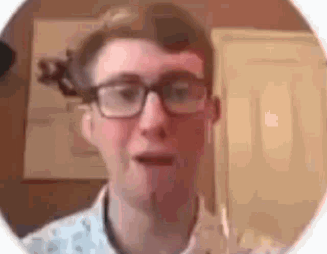 a young man wearing glasses and ear buds is talking to someone .