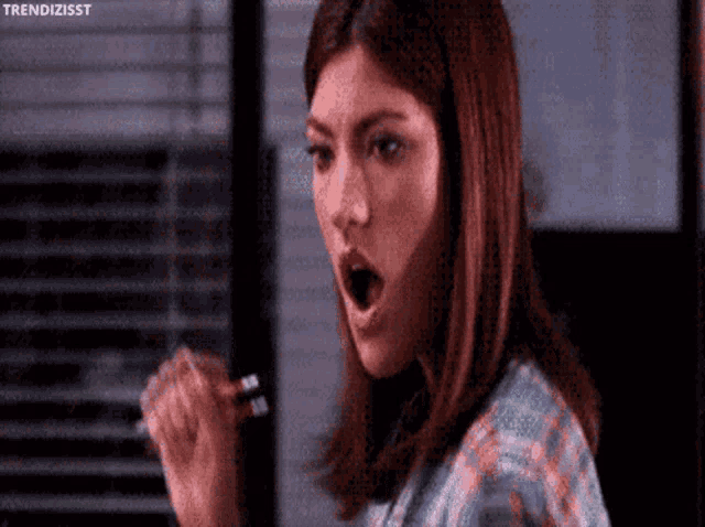 a woman is holding a pen in her hand and making a funny face .