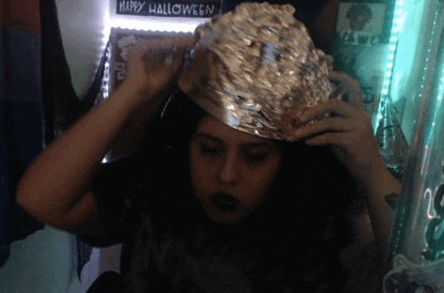 a woman is wearing a tin foil hat in front of a happy halloween sign