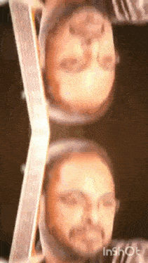 a close up of a man 's face with a beard and glasses in a mirror .