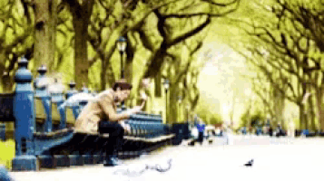 a person sitting on a bench in a park looking at their phone