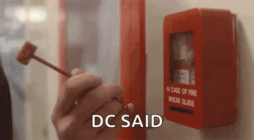 a person is holding a hammer in front of a fire alarm box .
