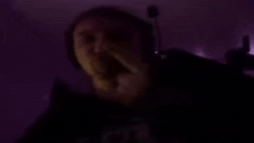 a man wearing headphones and a microphone is dancing in a dark room .