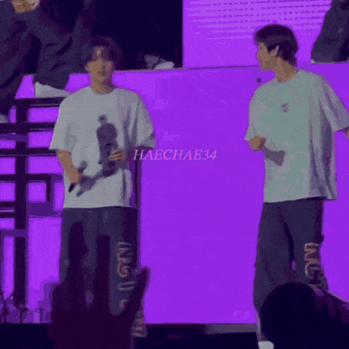 a man holding a microphone stands next to another man with the name haechae34 on the screen