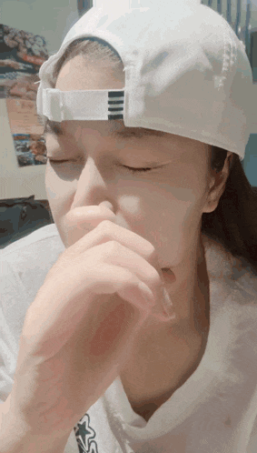a woman wearing a white adidas hat covering her mouth