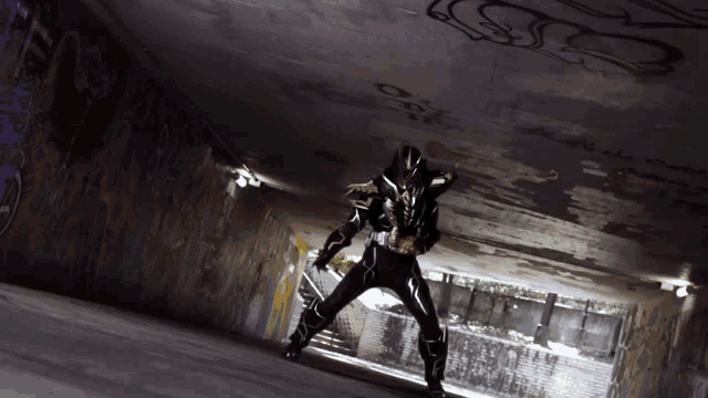 a man in a black costume is standing in a dark tunnel