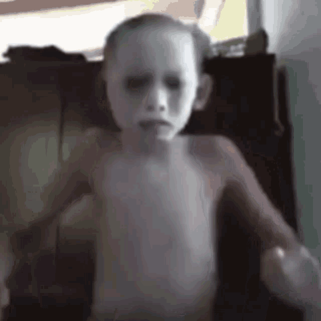 a shirtless child with a white face is standing in a room .