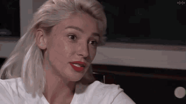a woman with blonde hair and red lips is wearing a white t-shirt