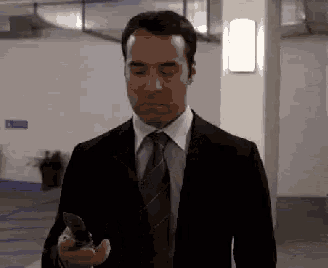 a man in a suit and tie is holding a cellphone