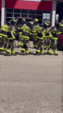 a group of firefighters are standing in front of a building