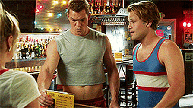 a man in a crop top is talking to another man in a tank top