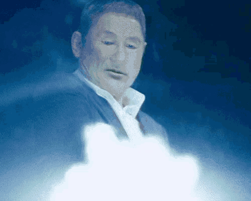 a man in a suit and white shirt is standing in front of a cloud in the sky .