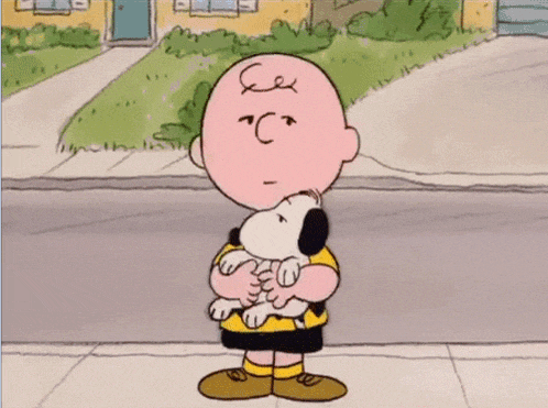a cartoon of charlie brown holding snoopy in his arms .