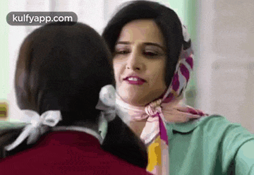 two women are standing next to each other and one of them is wearing a scarf around her head .