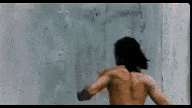 a naked man is standing in front of a wall
