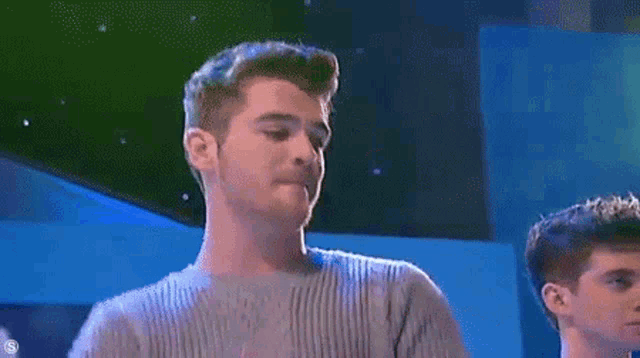 a man in a grey sweater is making a funny face