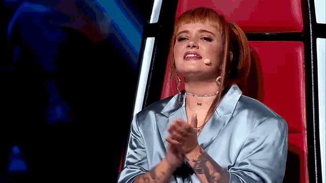 a woman with red hair is sitting in a red chair clapping