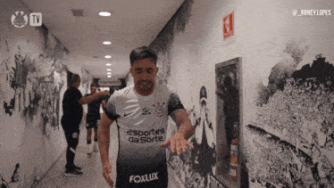 a man in a sports da sorte jersey walks through a hallway