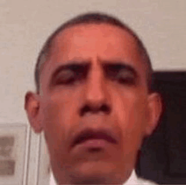 barack obama is taking a selfie with his eyes closed and making a funny face .