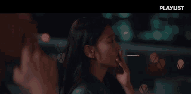 a woman is smoking a cigarette in front of a playlist ad