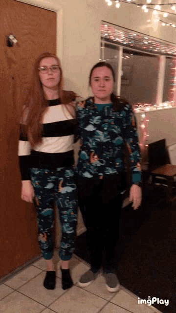 two women standing next to each other in front of a door in a room with christmas lights on the ceiling