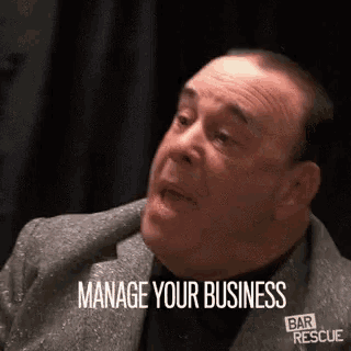 a man in a suit is talking to another man and says manage your business .