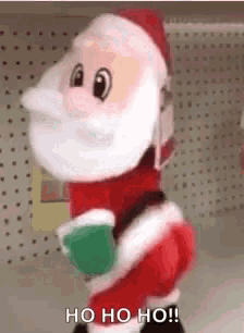a stuffed santa claus is standing in front of a shelf in a store holding a cup of coffee .