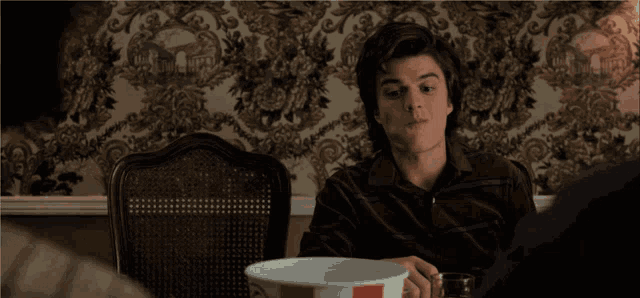 a man is sitting at a table with a bucket of kfc in his hand