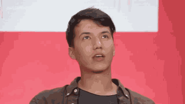 a young man in a brown shirt is looking up at the sky .