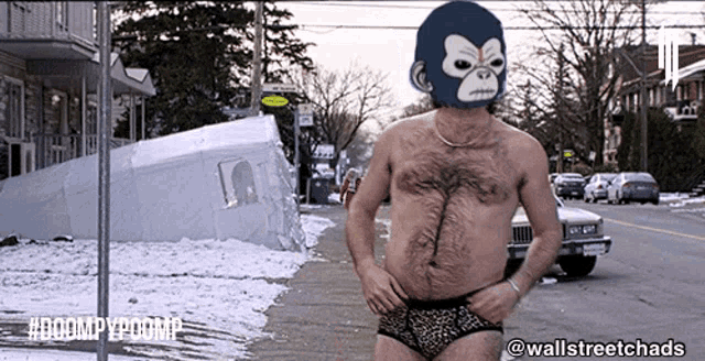 a shirtless man wearing a gorilla mask stands on a street