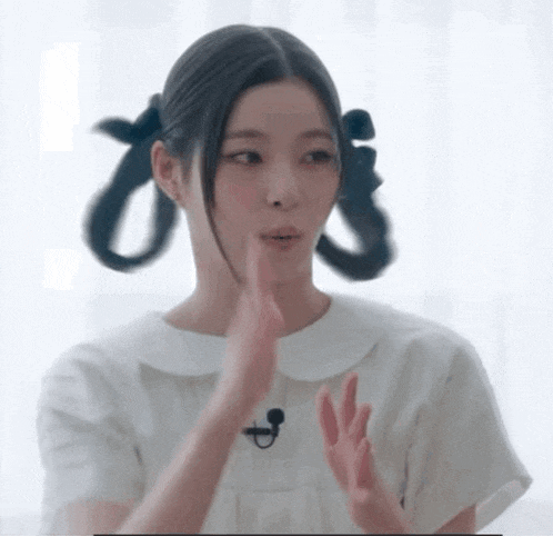 a woman with pigtails on her hair is wearing a white shirt and a microphone .
