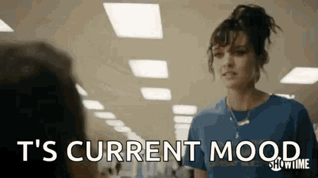 a woman in a blue shirt is standing in a hallway with the words `` t 's current mood '' .