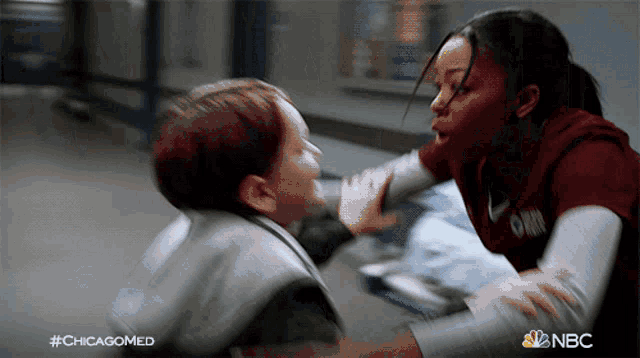 a woman in a chicagomed shirt holds a child 's hand