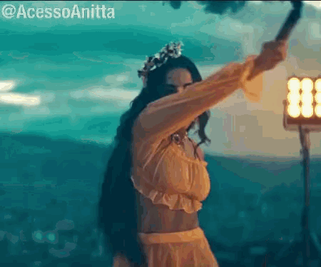 a woman in a yellow dress and a flower crown is holding a torch .