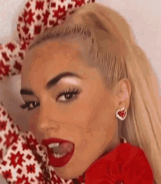 a close up of a woman wearing red lipstick and earrings with her mouth open .