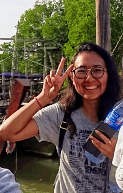 a woman wearing a shirt that says " a way to remember " holds a bottle of aquafina water